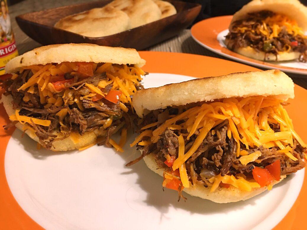 A group of people enjoying smoked brisket arepas at an outdoor gathering
