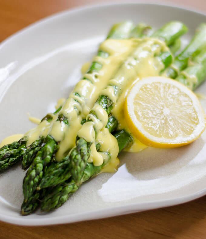 person blending asparagus and lemon in a blender