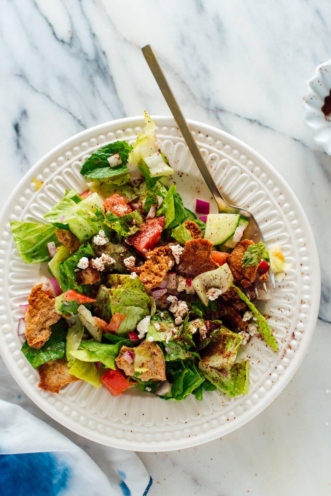 A bowl of mint and peanut fattoush salad being dressed with sesame dressing