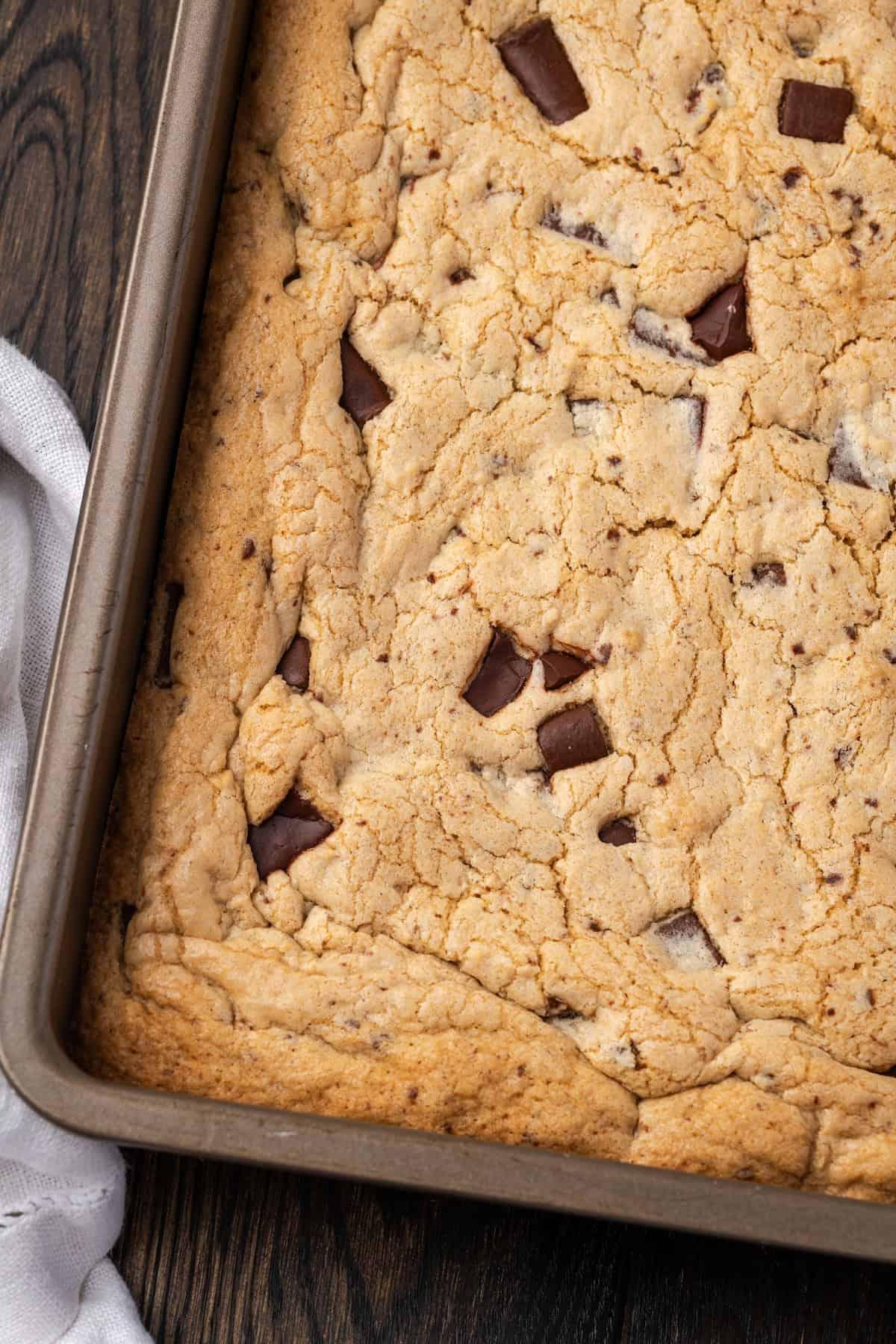 Overhead shot of a baking pan filled with golden-brown gooey chocolate chip cookie bars, freshly out of the oven