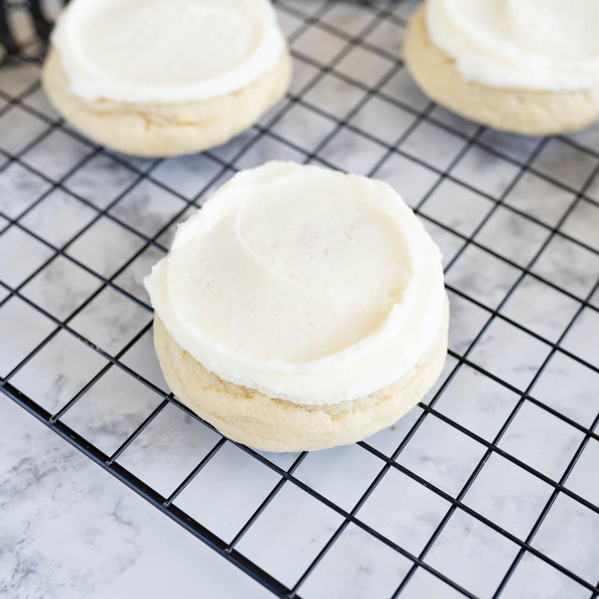 A close-up of a single vanilla crumb sugar cookie on a rustic wooden board, crumbs visible