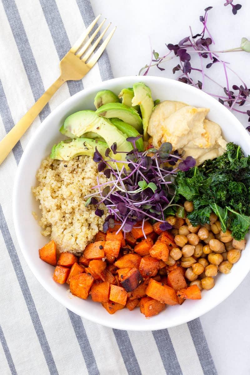 Person enjoying a sweet potato and quinoa bowl with a fork