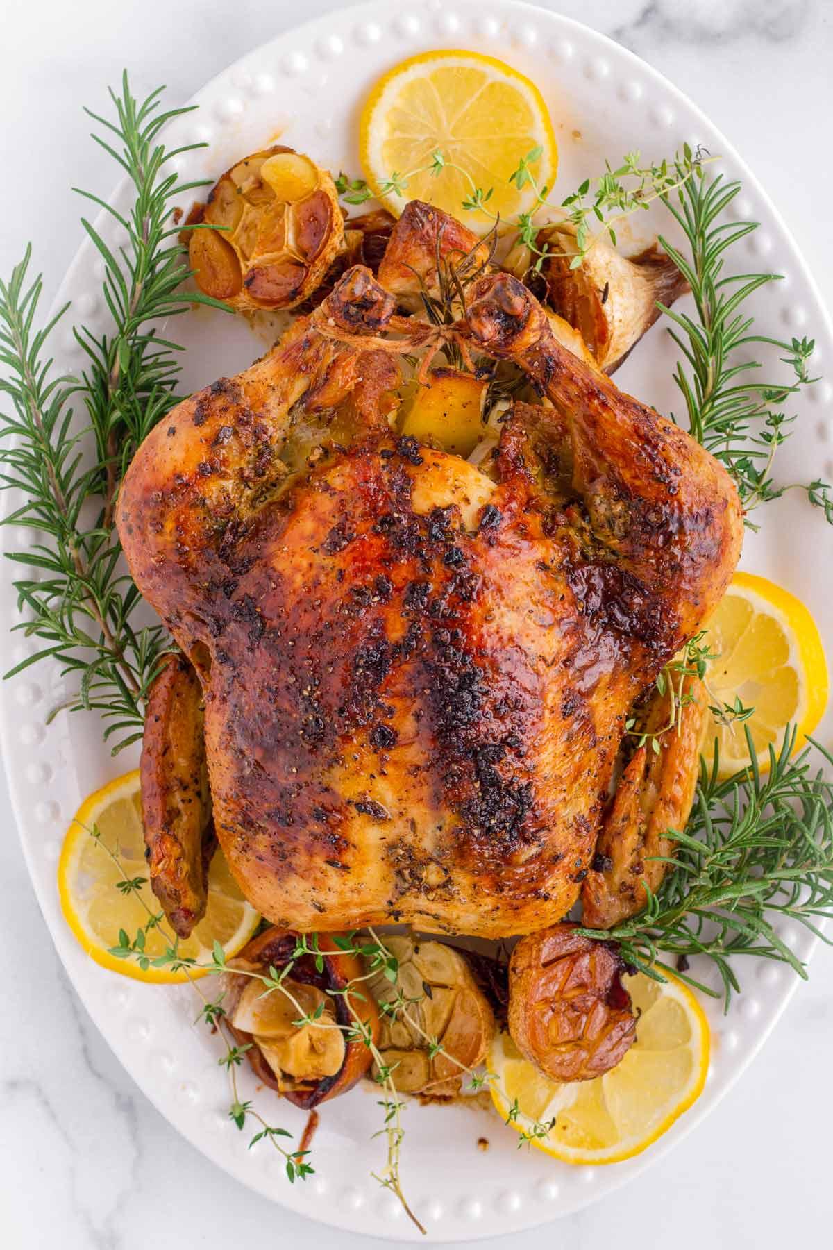 golden brown lemon herb roasted chicken on a platter