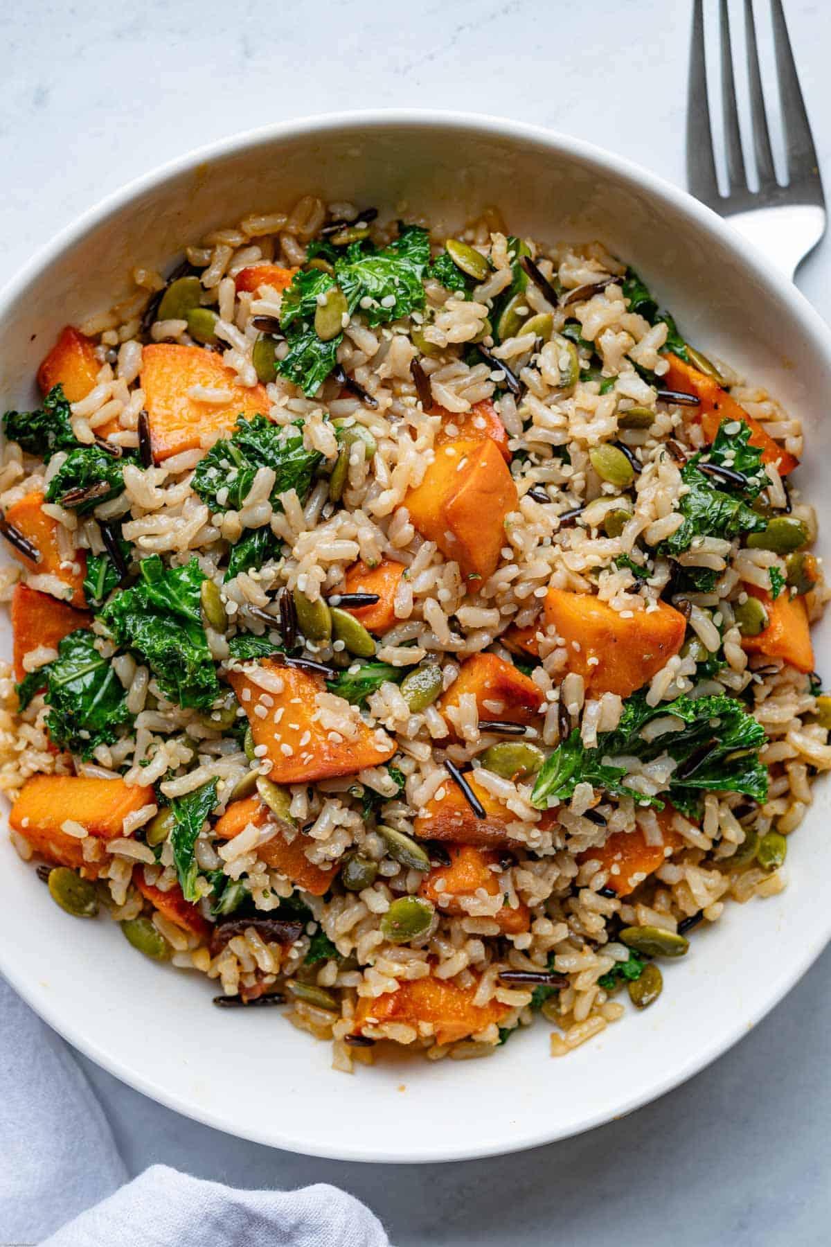close up of a bowl of steamed rice with sweet potato and kale