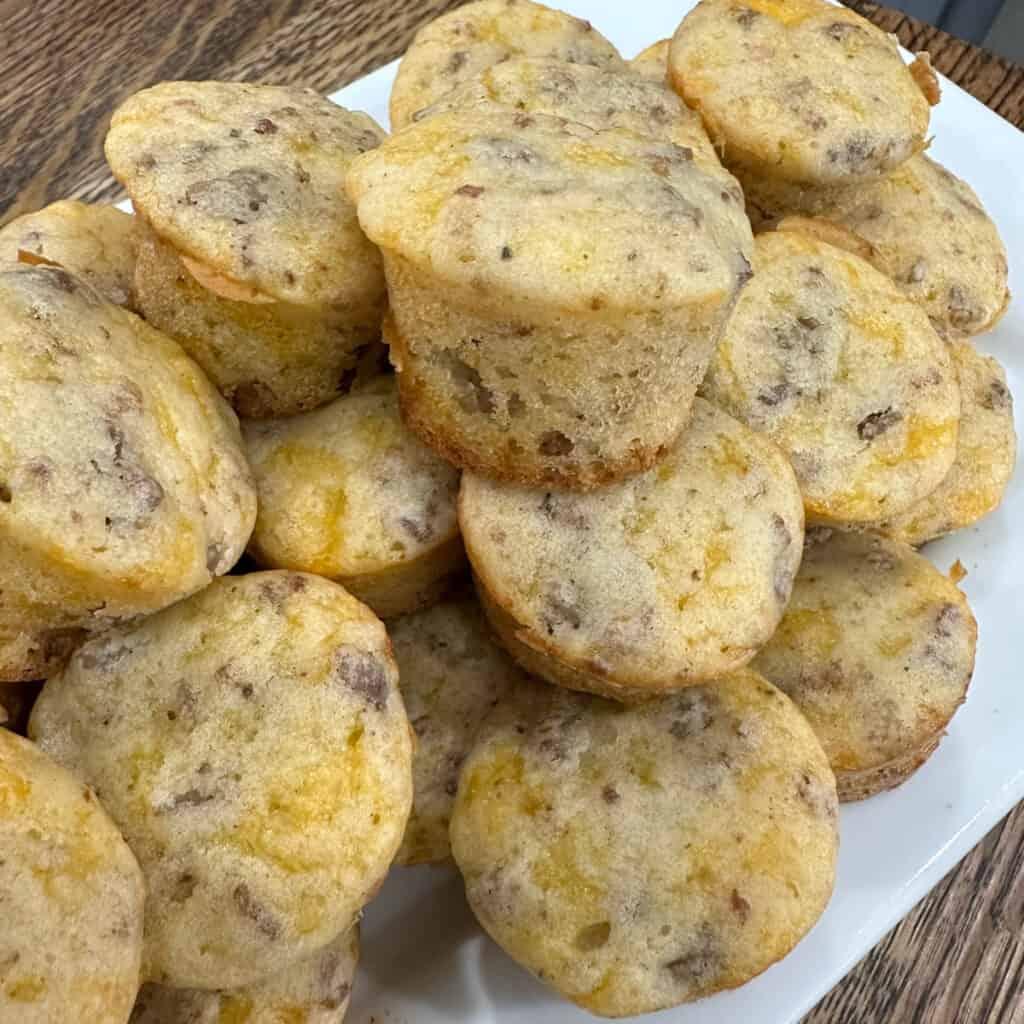 A close-up shot of several miniature McGriddle bites cooking on a hot griddle, showing bubbles forming in the batter