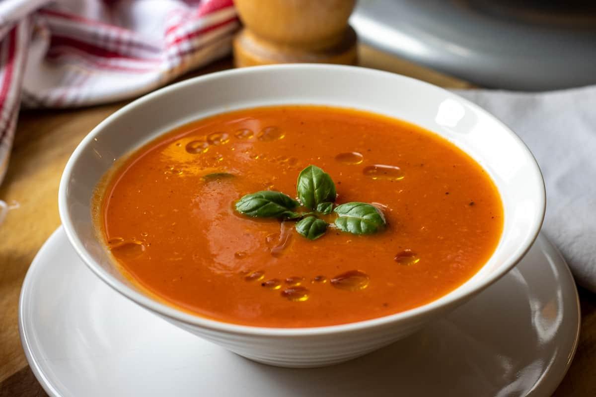 A vibrant bowl of Keto Roasted Red Pepper and Tomato Soup, garnished with fresh basil