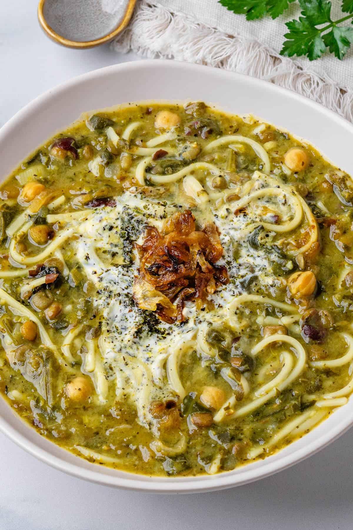 bowl of vegan Ash Reshteh garnished with fried mint and crispy onions