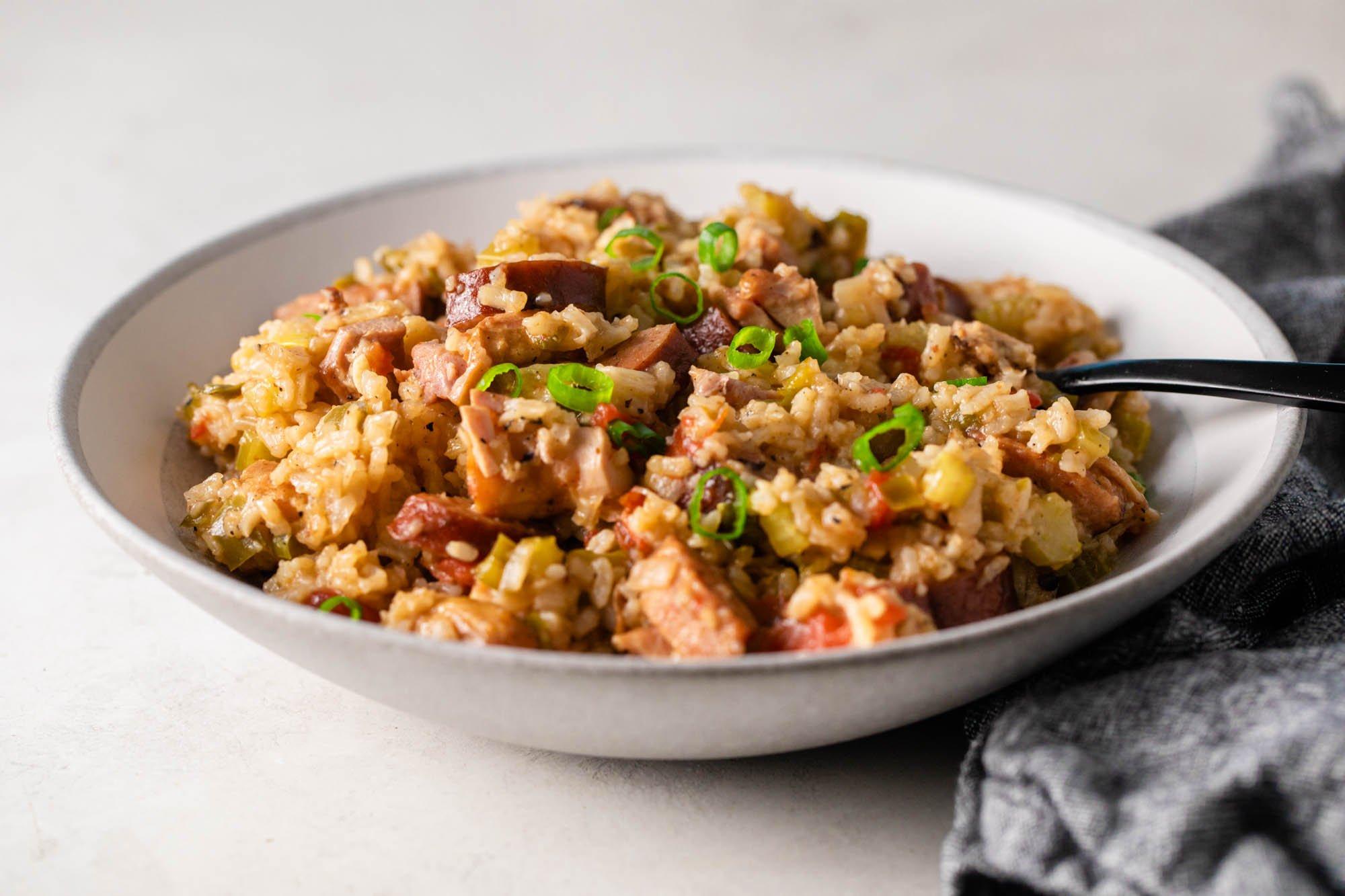 A steaming bowl of Kimchi Jambalaya with Andouille Sausage, garnished with green onions and parsley