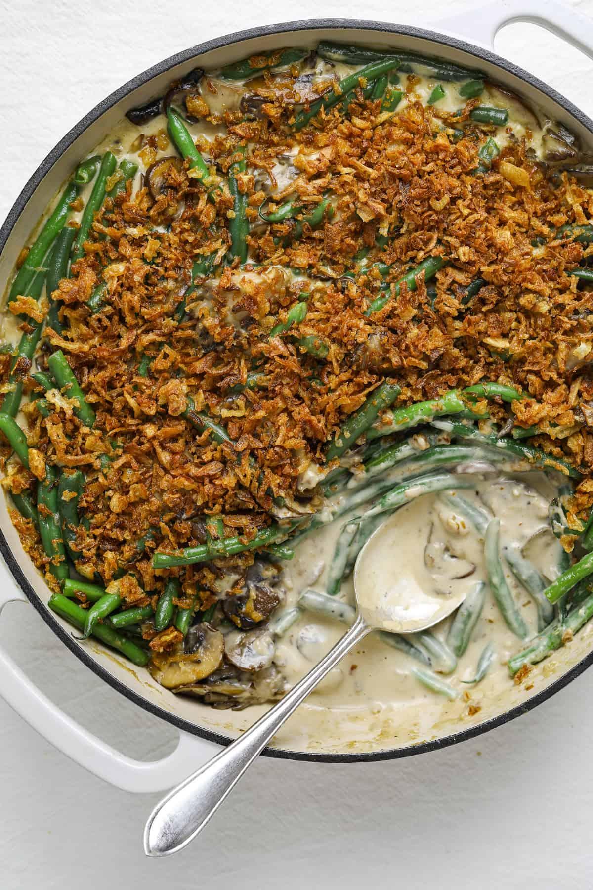 Close-up of a bubbling green bean casserole, fresh mushrooms visible in the creamy sauce