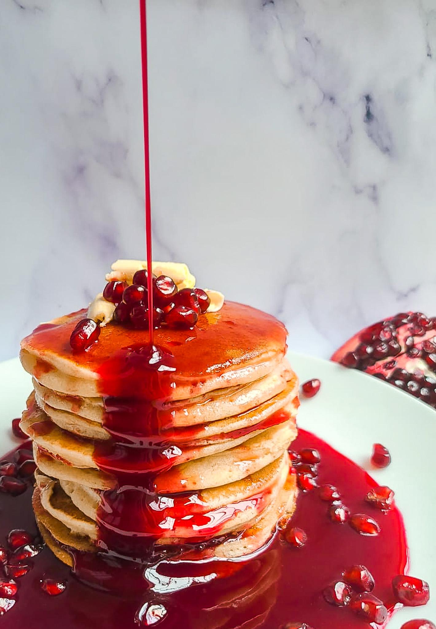 close-up of pomegranate pancakes with syrup dripping down