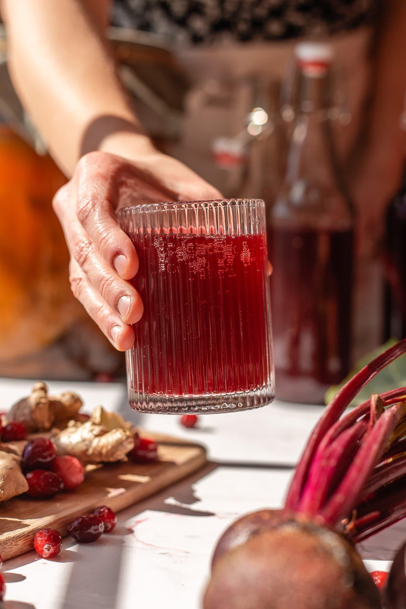 Person enjoying a glass of cranberry vanilla kombucha