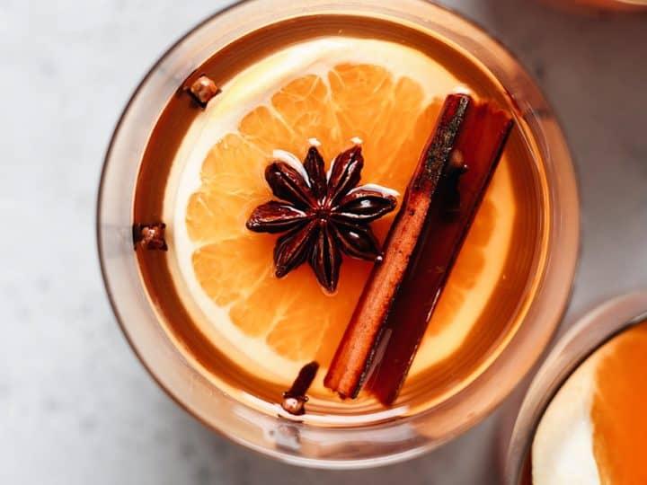 Close-up of Friendsgiving Velvet Maple Cider in a ceramic mug, steam rising, with cinnamon sticks and star anise garnishes