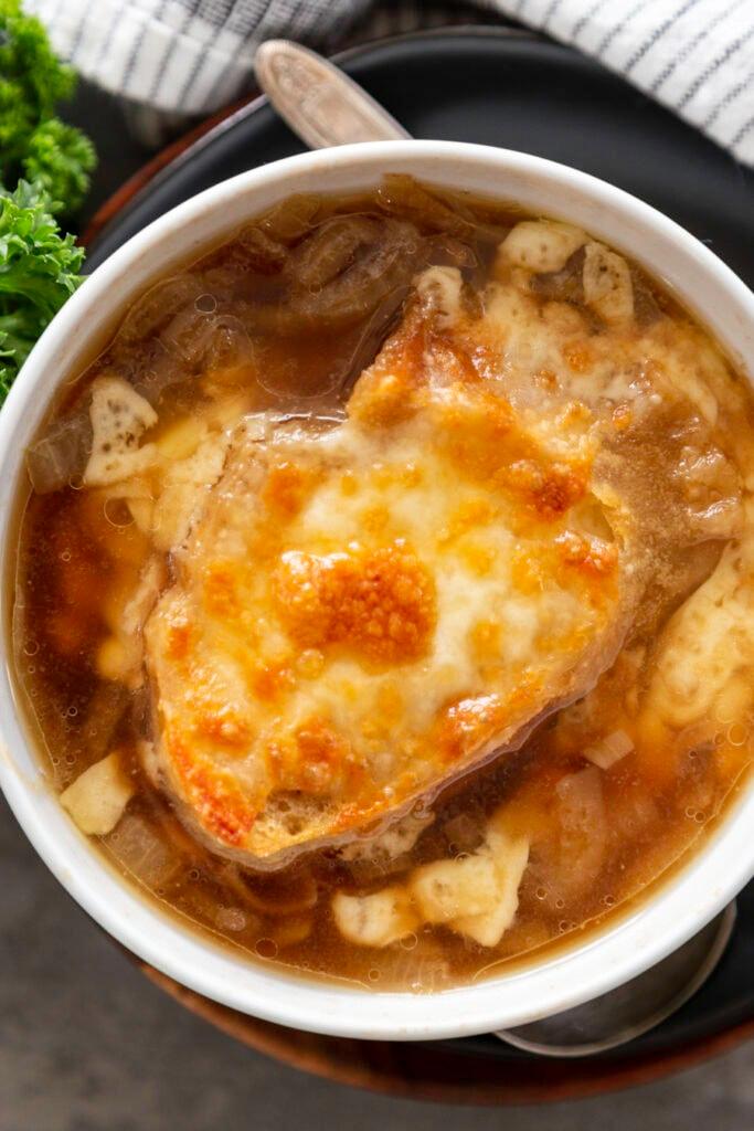 A person enjoying a bowl of Instant Pot French onion soup with Gruyere cheese