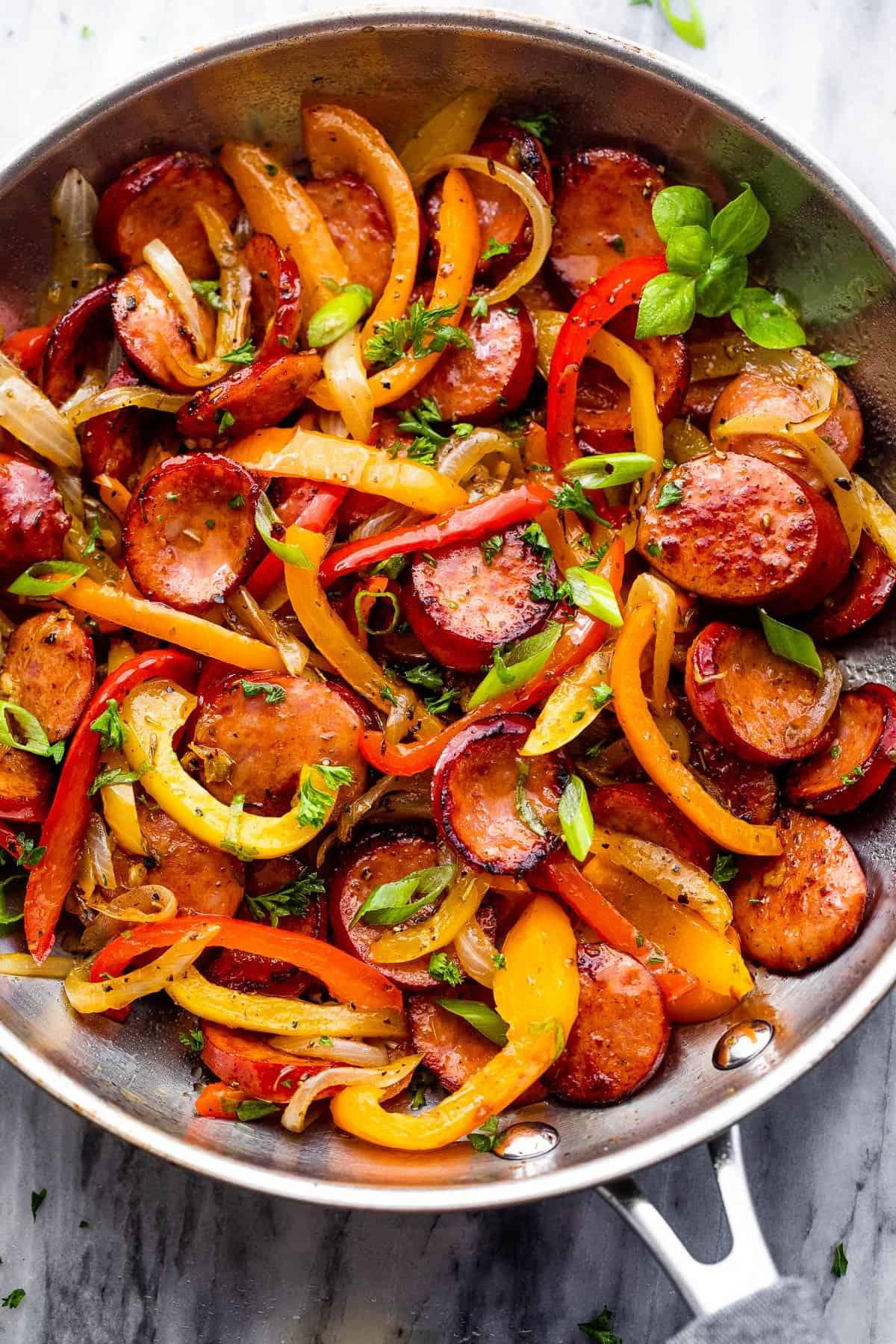 sausage and peppers cooking in a large skillet