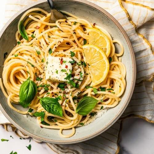 A vibrant bowl of garlic herb pasta, garnished with fresh parsley and parmesan, ready to eat, cozy kitchen background with warm lighting