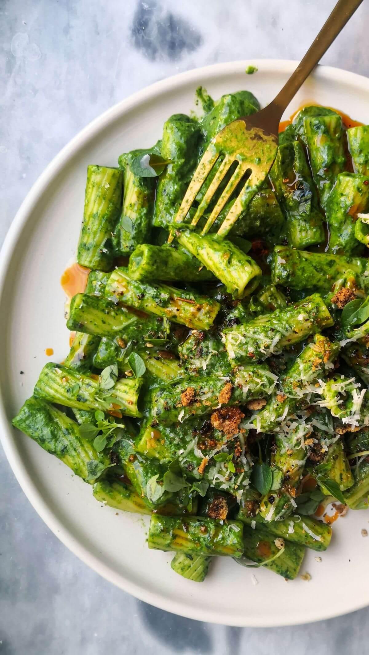 vibrant green pasta dish with arugula and parmesan cheese