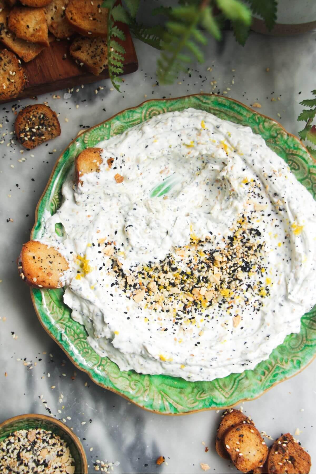 close-up of someone dipping pita bread into everything bagel tzatziki