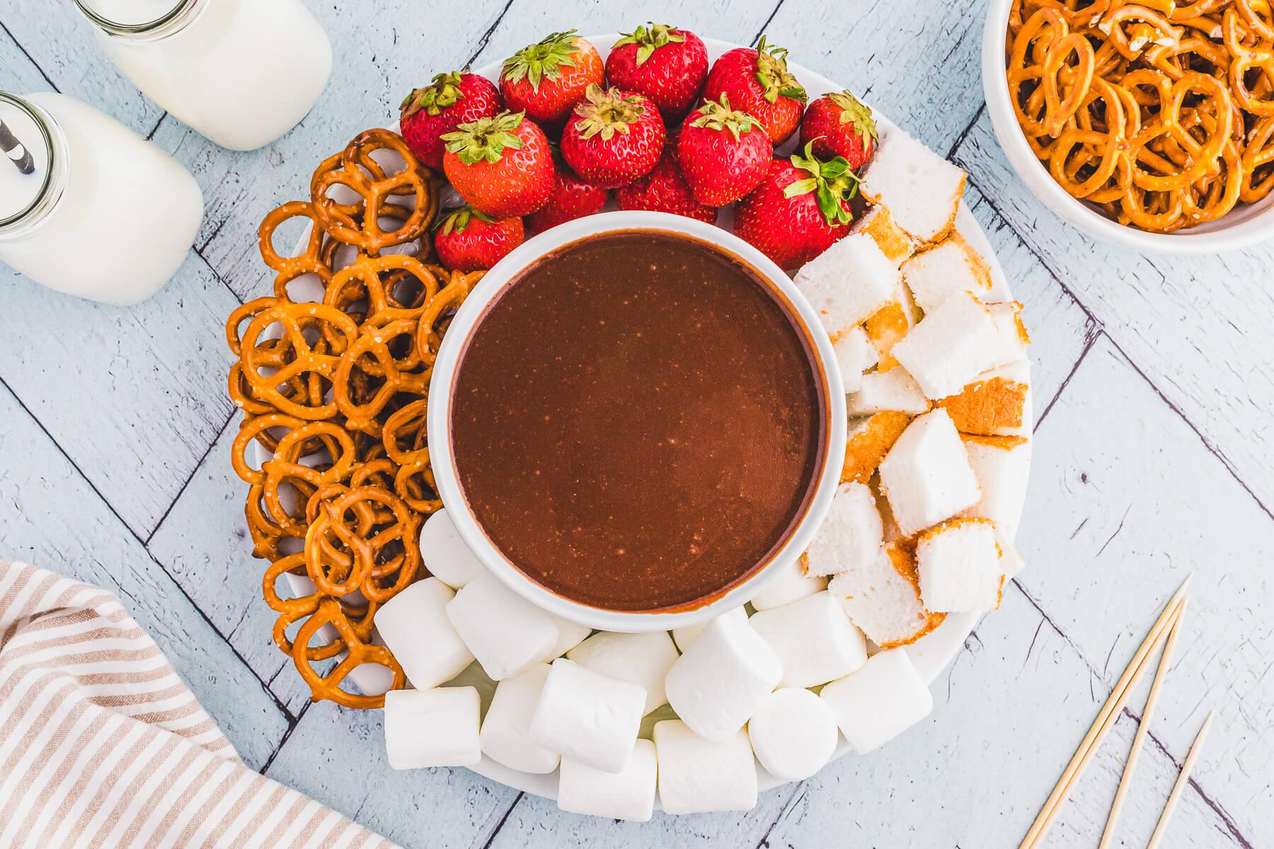 Chocolate fondue with various dipping ingredients arranged around it