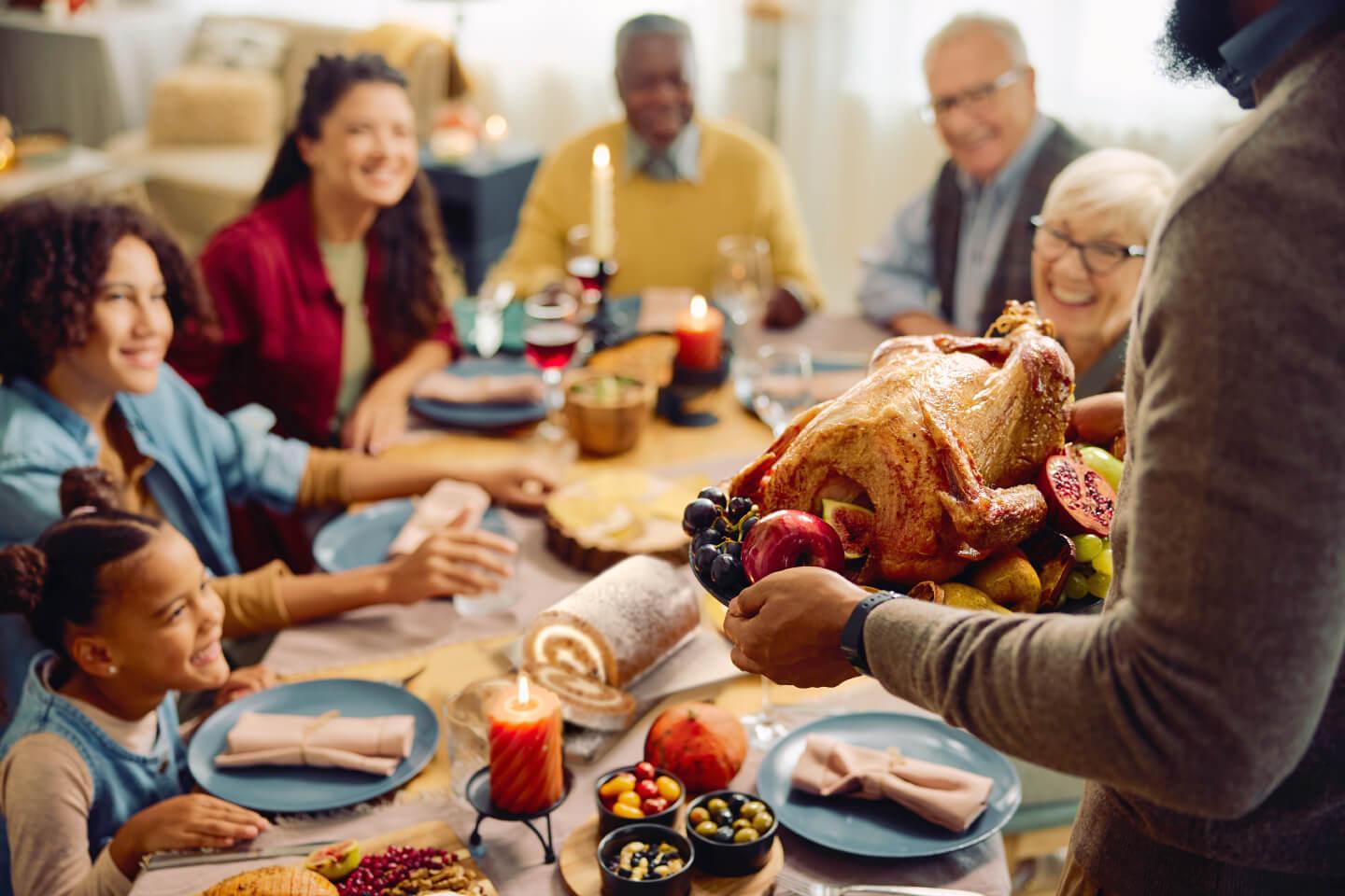 Family gathered around a dining table with a beautifully roasted turkey centerpiece