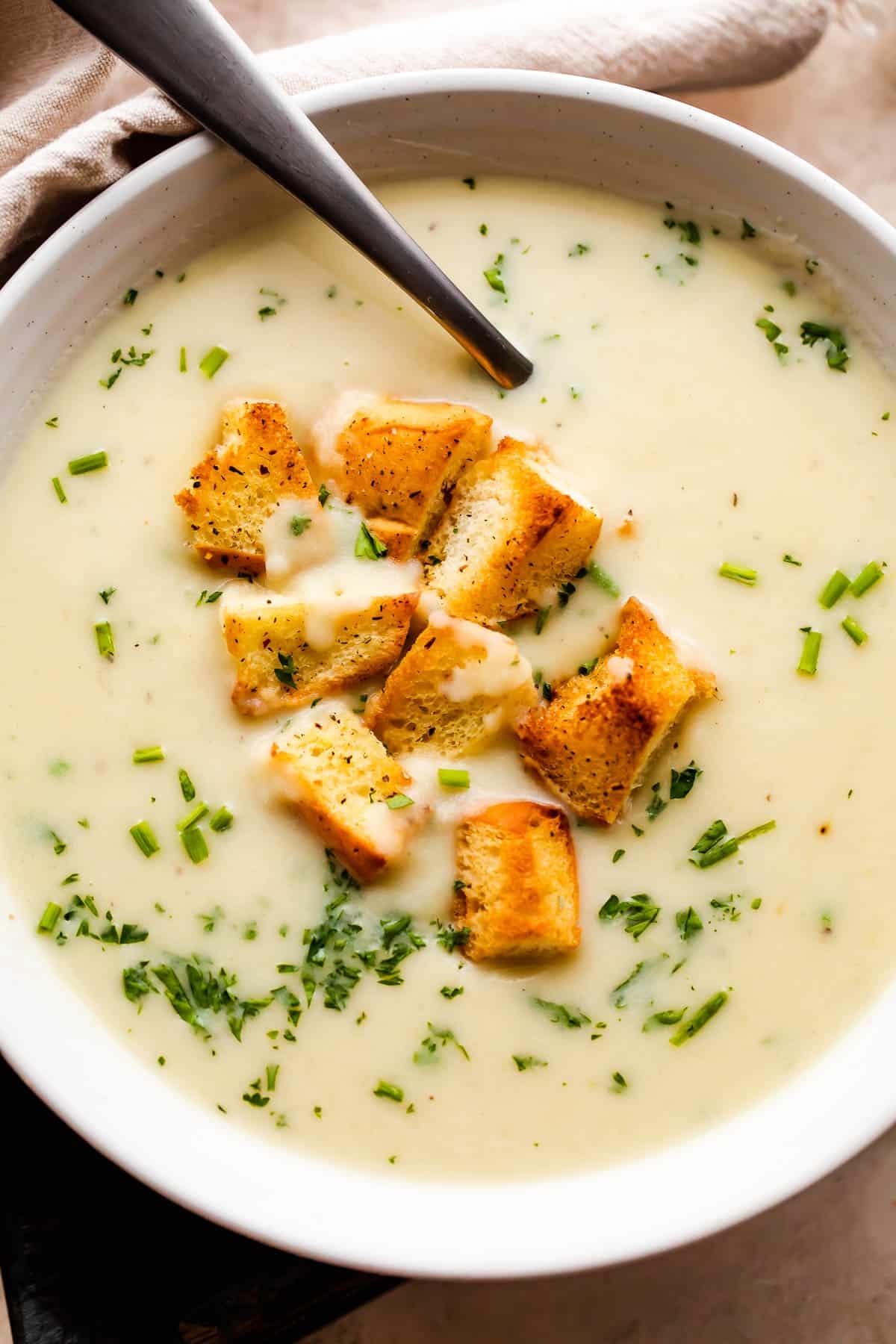 Overhead shot of creamy potato leek soup with a swirl of cream and fresh parsley