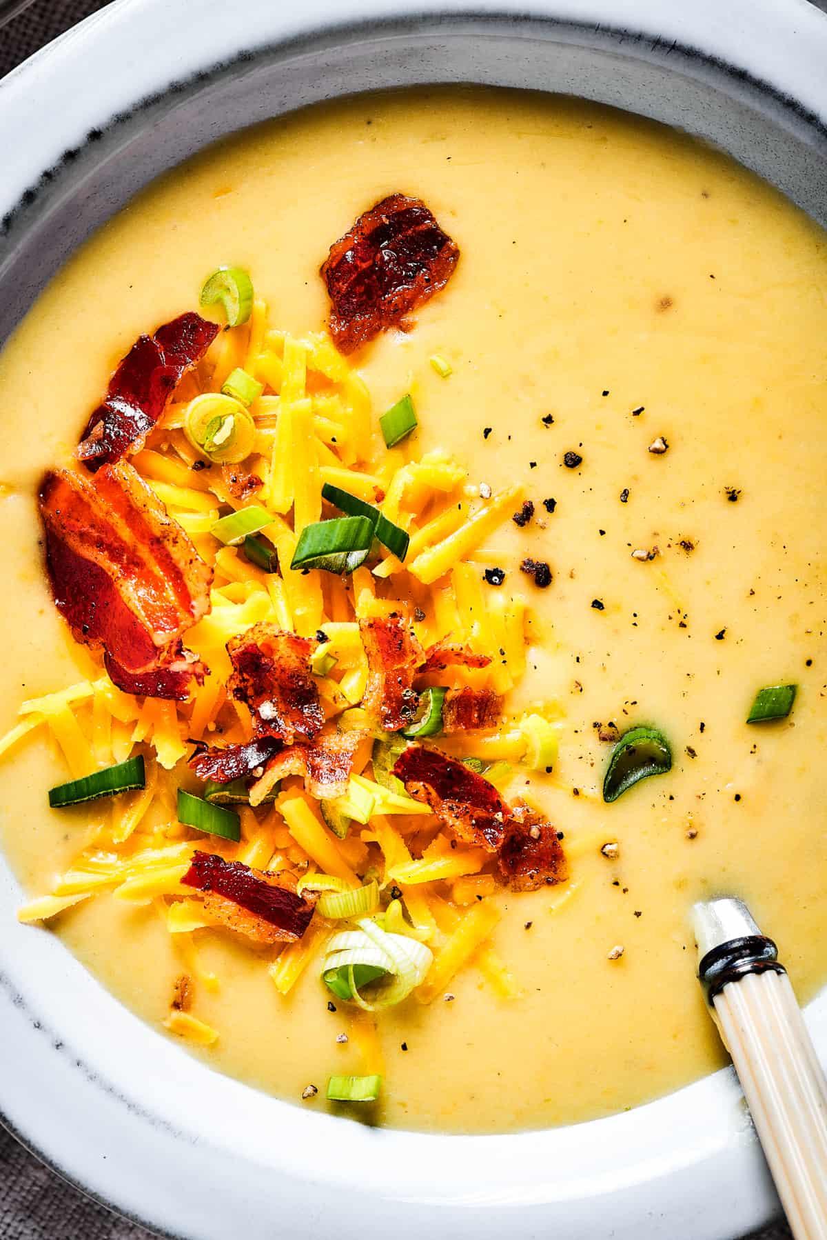 close-up shot of creamy loaded baked potato soup being stirred in a pot