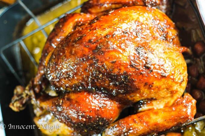 close up shot of a person basting a turkey with a maple-mustard glaze