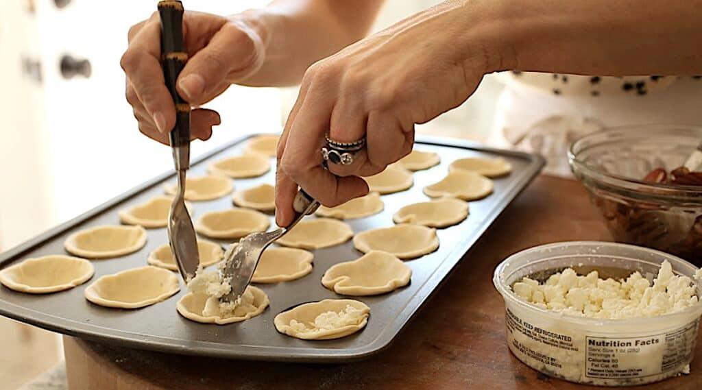 person assembling mini cheese tarts in a muffin tin