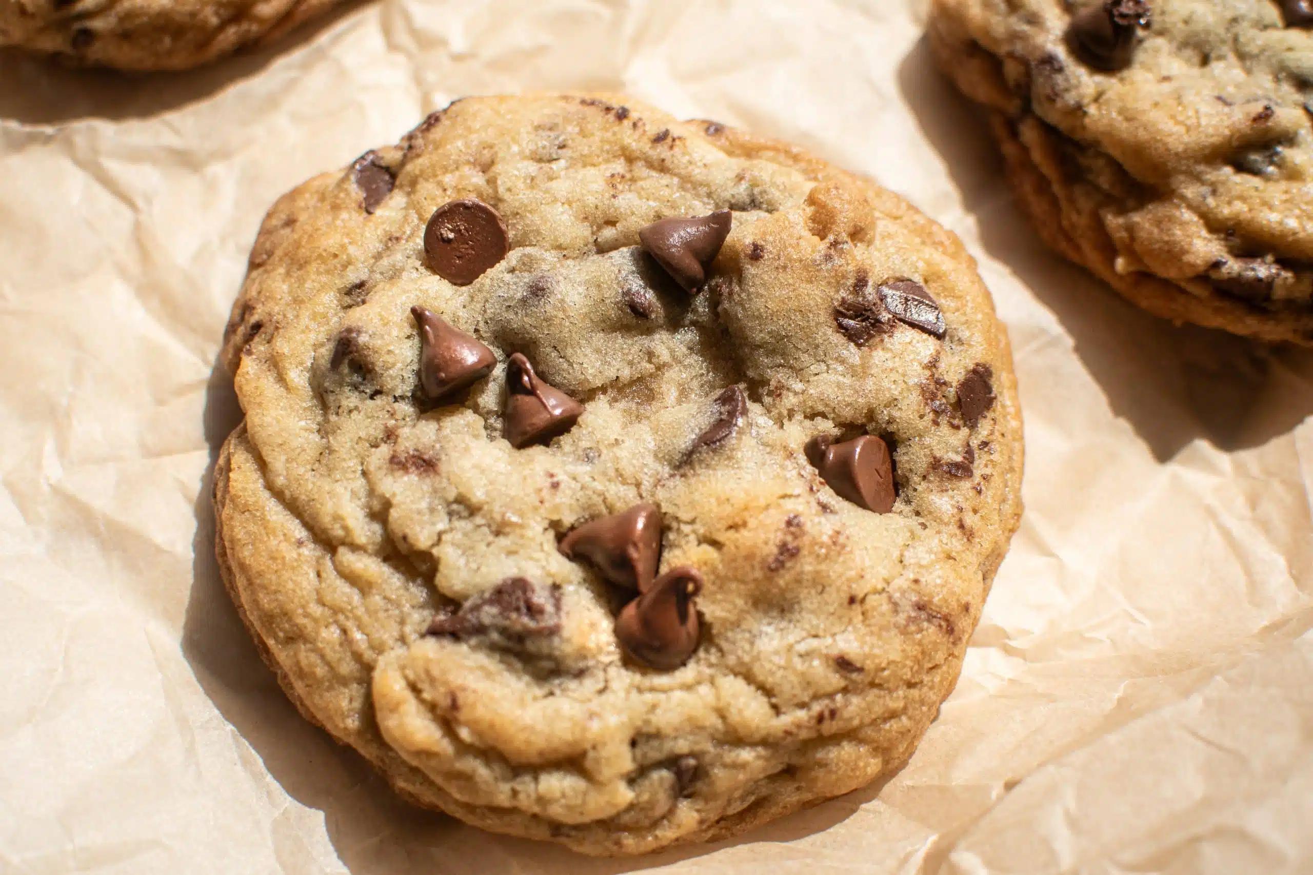 close up of a batch of freshly baked peanut butter sea salt chunk cookies on a baking sheet