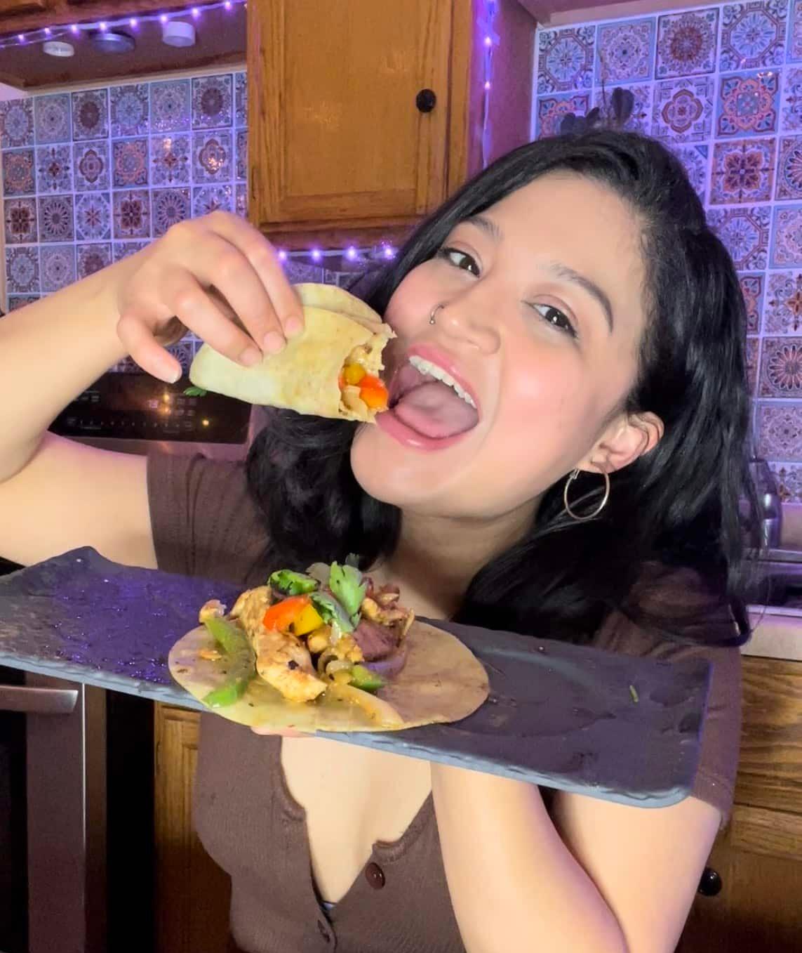 woman happily biting into a fajita chicken samosa