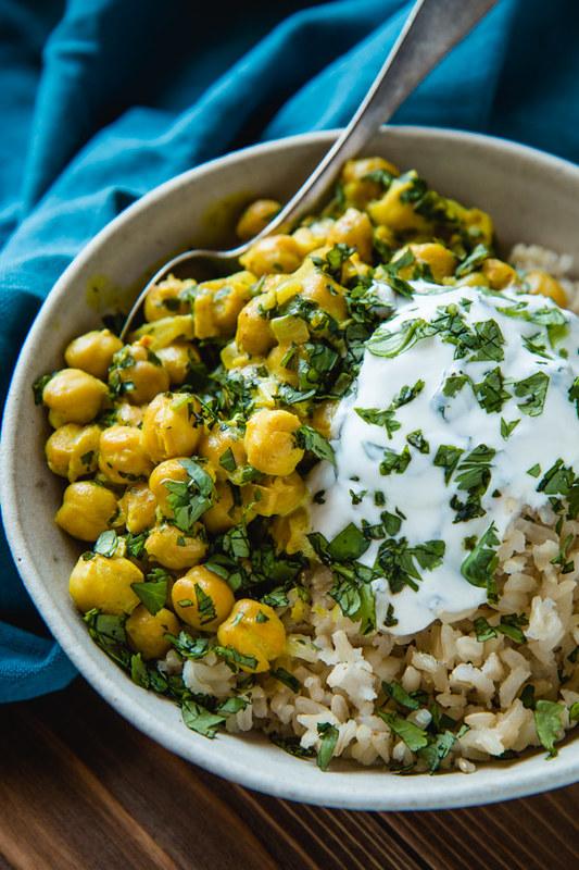 overhead shot of chickpea curry in a bowl with coconut yogurt and mint