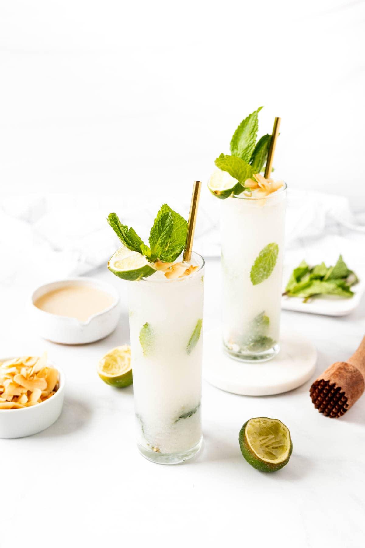 overhead shot of several coconut mojitos in tall glasses with ice and garnishes