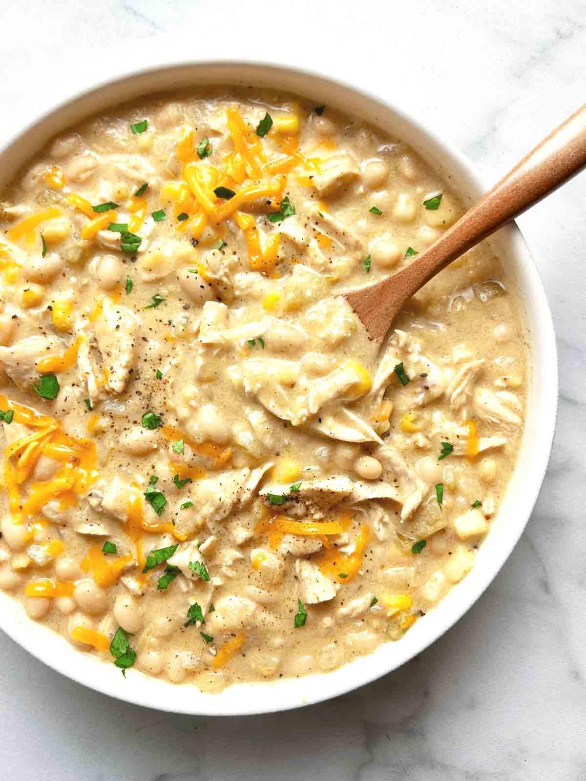 close-up of white chicken chili being stirred in a large pot