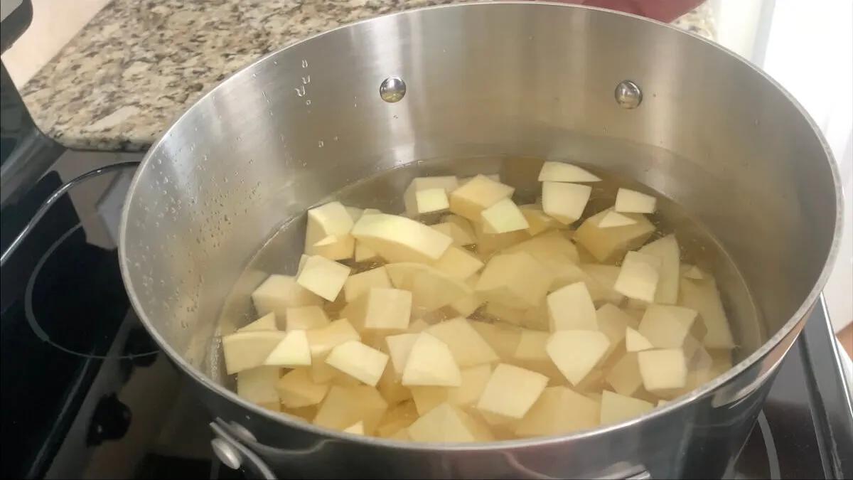 Close-up shot of diced rutabaga being added to boiling water, steam rising from the pot