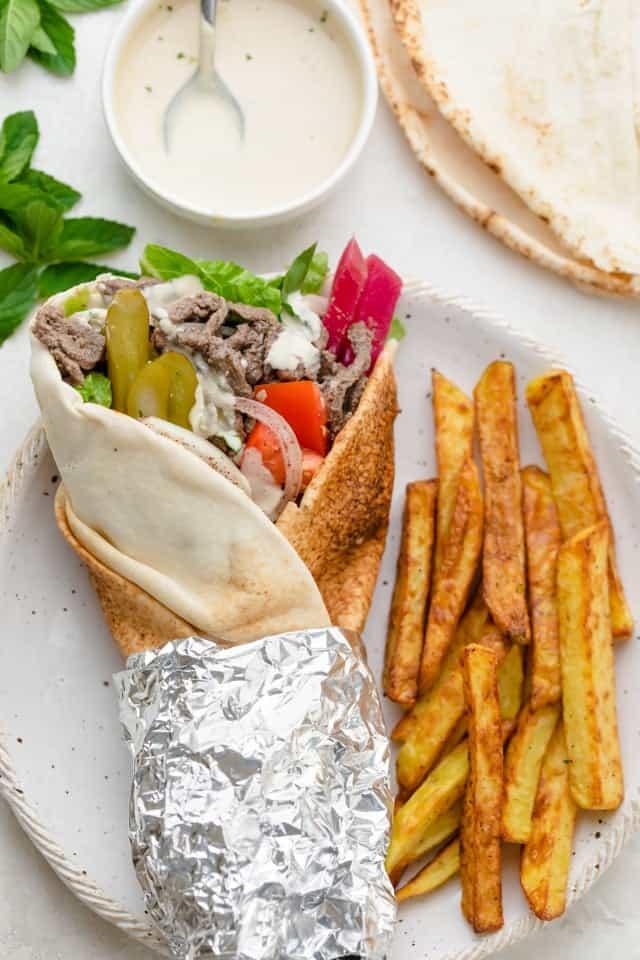 Beef shawarma served in warm pita bread with tzatziki sauce and fresh vegetables, ready to eat