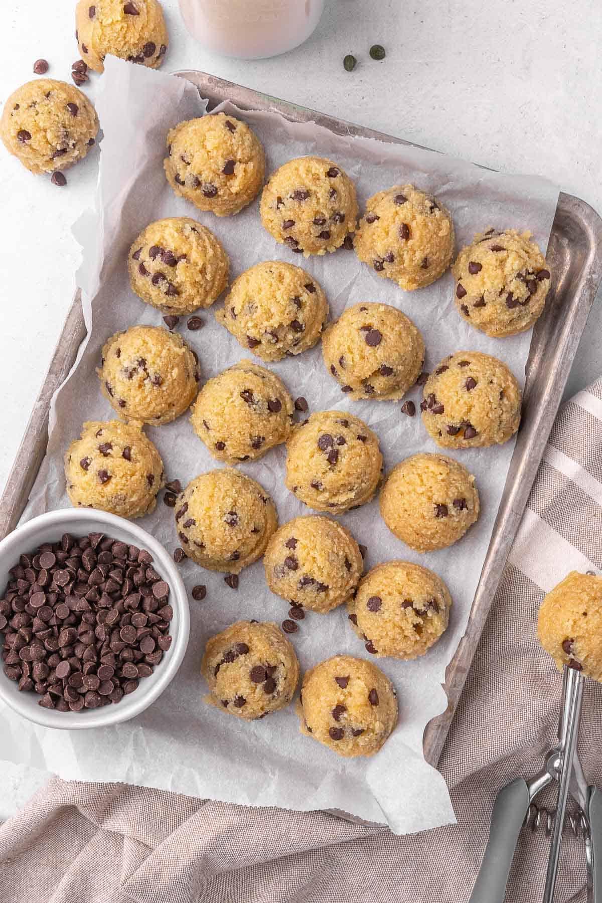 raw chocolate orange cookie dough balls on a parchment-lined baking sheet