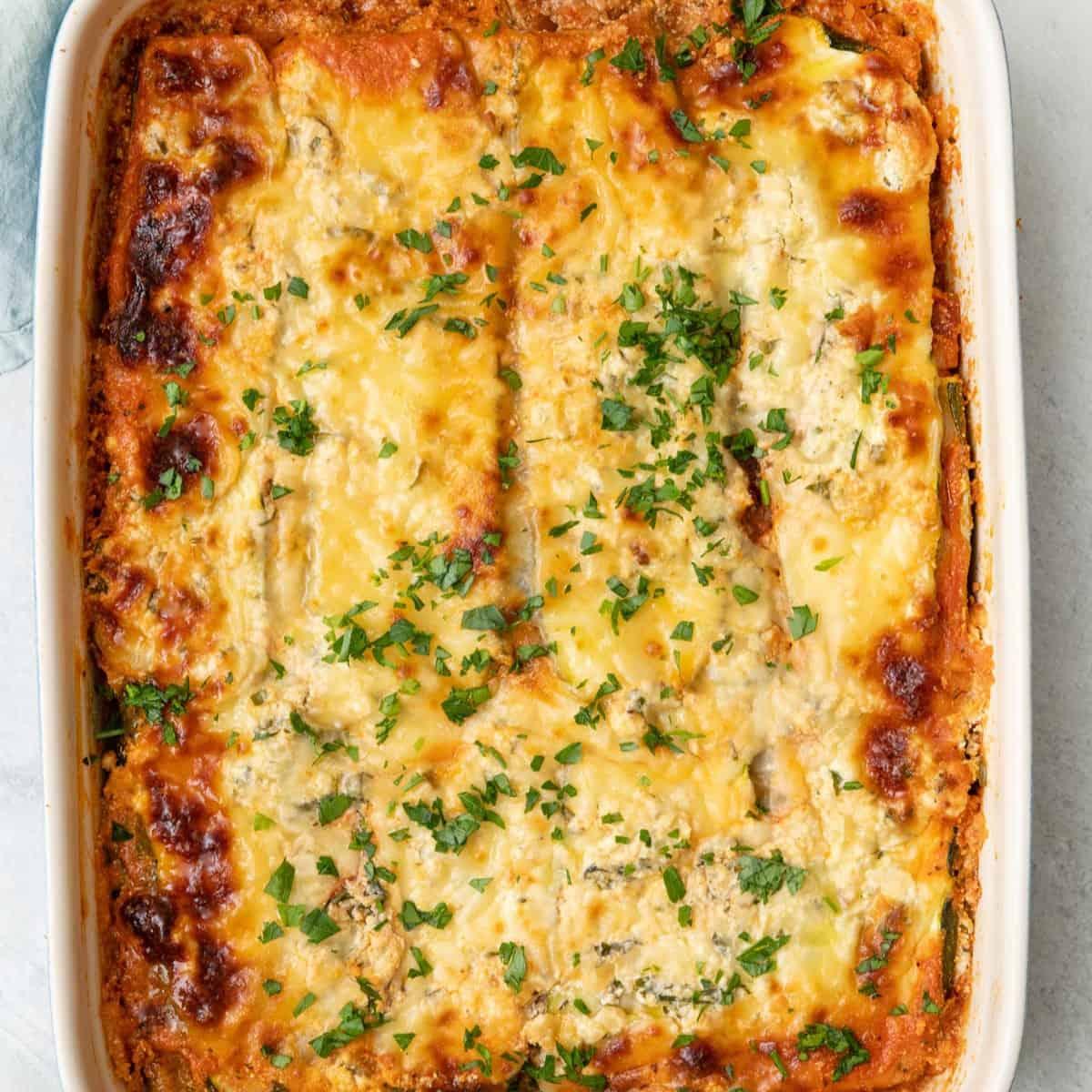 Close up shot of a vibrant, freshly made Zucchini Lasagna with a Mediterranean twist, garnished with fresh herbs.