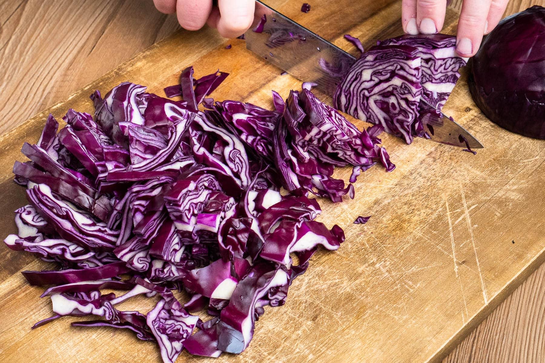 Close-up of thinly sliced red cabbage on a cutting board, ready for braising