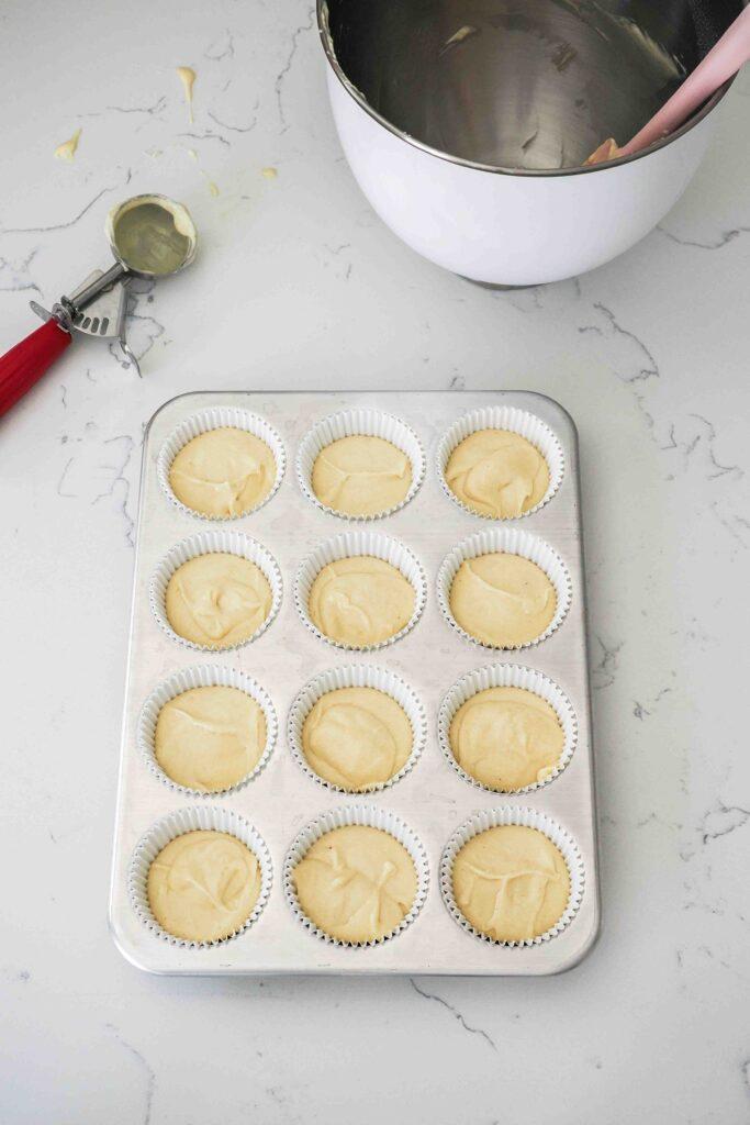 a batch of freshly baked vanilla bean cupcakes in a muffin tin