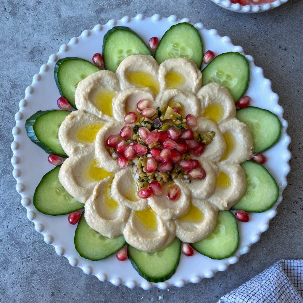 Close-up of fresh hummus being artfully spread on a round platter