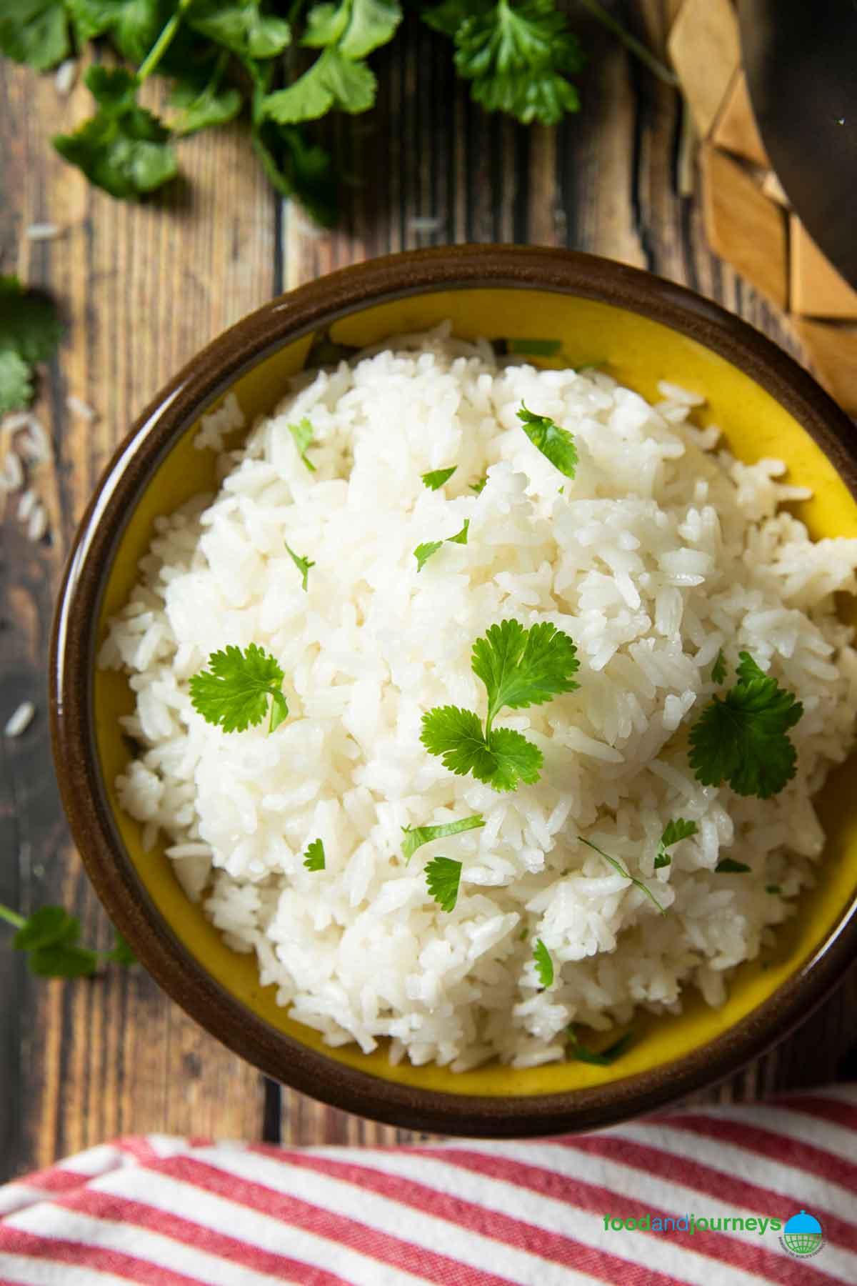 overhead shot of fluffy coconut rice in a bowl with garnishes