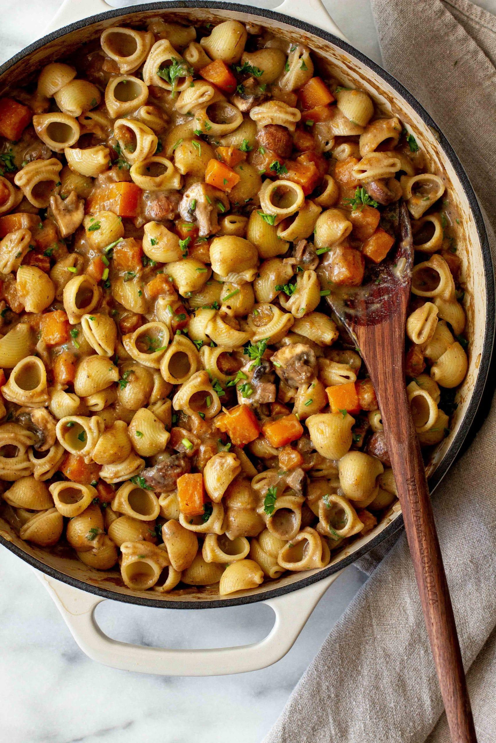 cooking butternut squash and mushroom pasta in a skillet