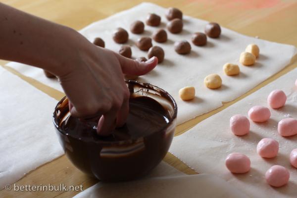 hands dipping a bonbon into melted chocolate