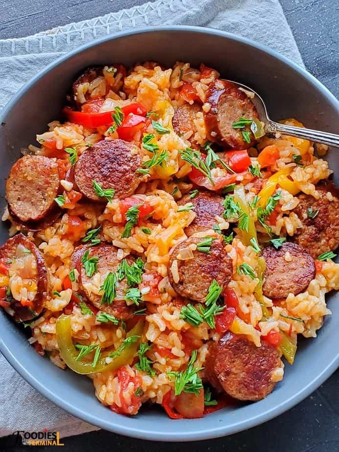 A person serving a bowl of Instant Pot Red Rice with Sausage and Peppers