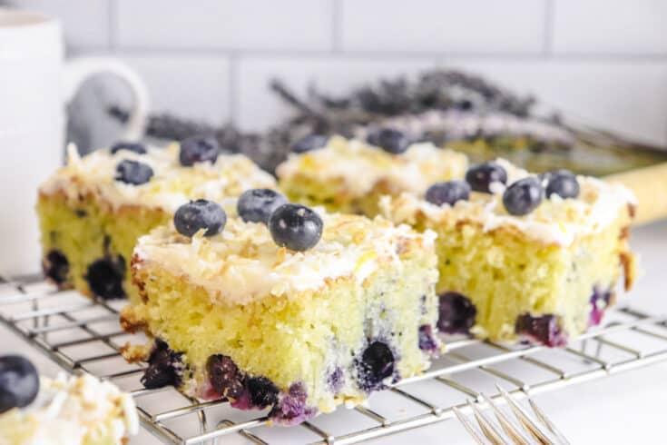 A rustic 9x13 inch baking pan filled with a golden, lemon blueberry cake, garnished with fresh lemon zest and blueberries