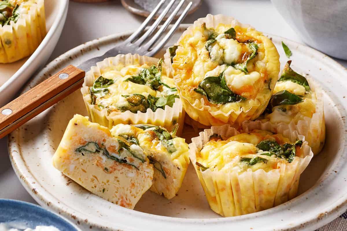 Hands scooping a portion of cheesy egg bake onto a plate