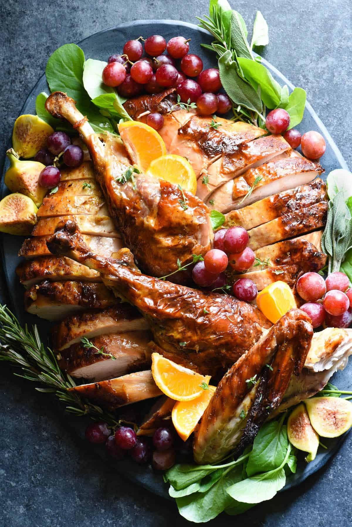 Overhead shot of a full, golden-brown roasted turkey on a serving platter with an array of colorful side dishes