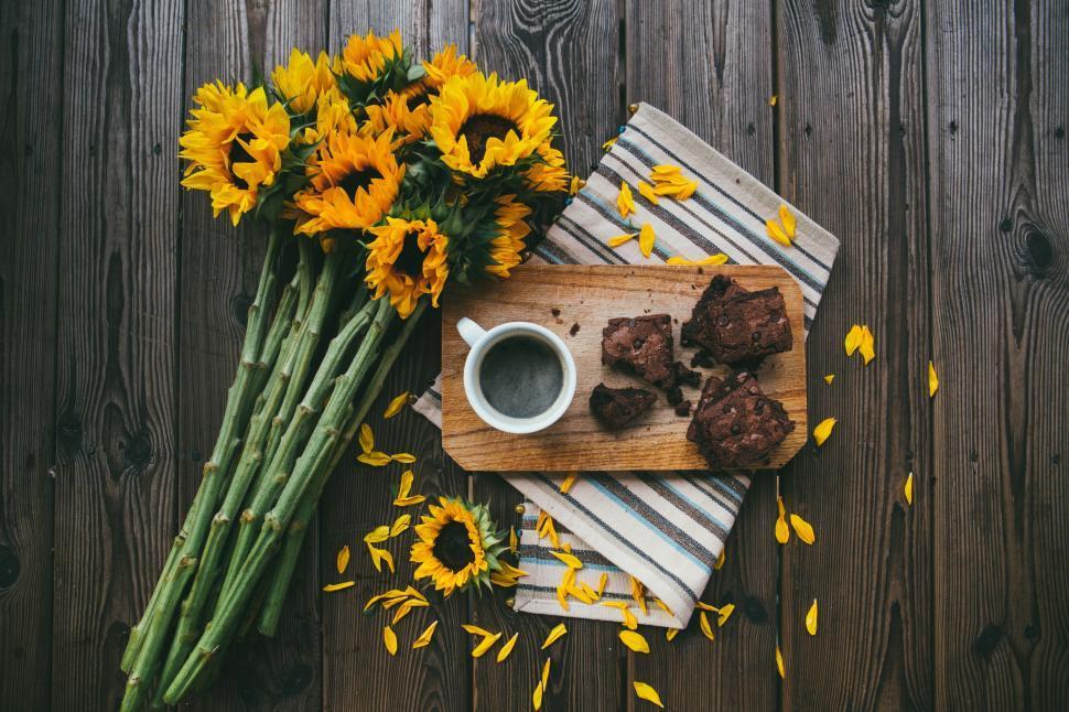 A rustic wooden table with a plate of golden wheat cakes, a cup of coffee, and a vase of wildflowers