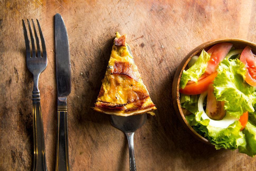A rustic wooden table set with a quiche, salad, and wine