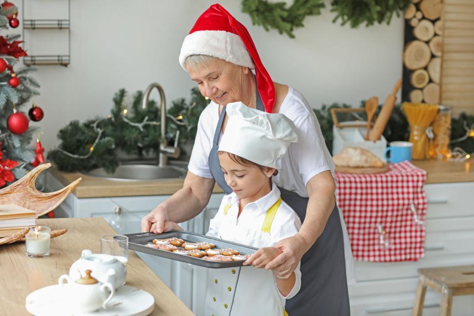 a child and grandmother baking gingerbread cookies together, warm kitchen lighting