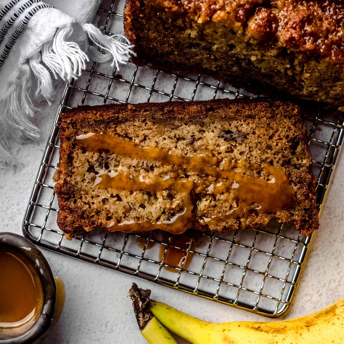 A full loaf of caramel banana ripple bread cooling on a wire rack, sun shining on it